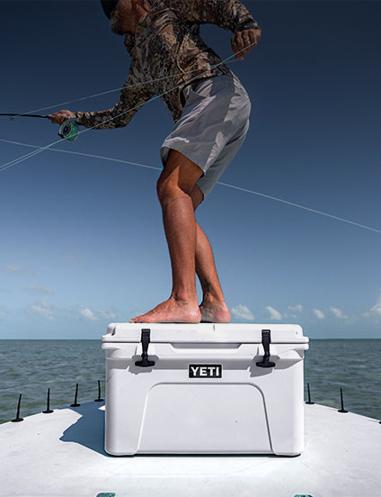 Person fishing on a YETI cooler by the water