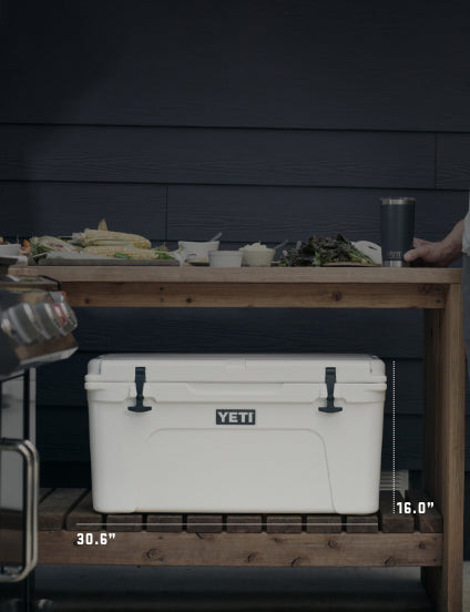 White YETI cooler on a wooden table with food and drinks in the background