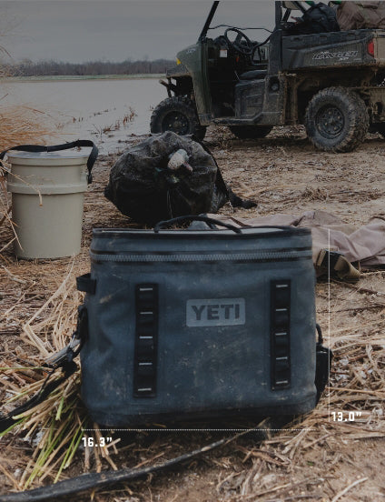 YETI cooler bag in a field with a vehicle and gear in the background