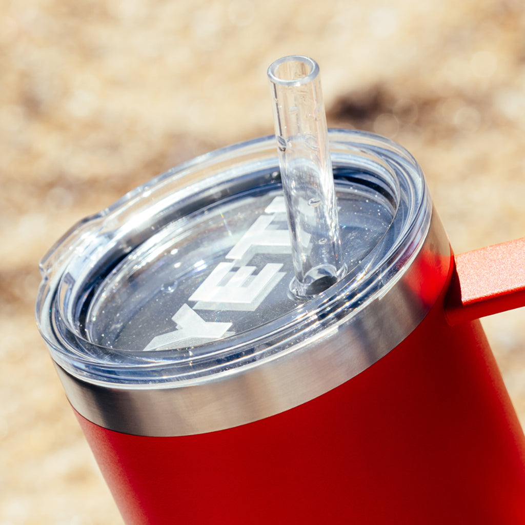 Red YETI mug with clear lid and straw on a blurred natural background