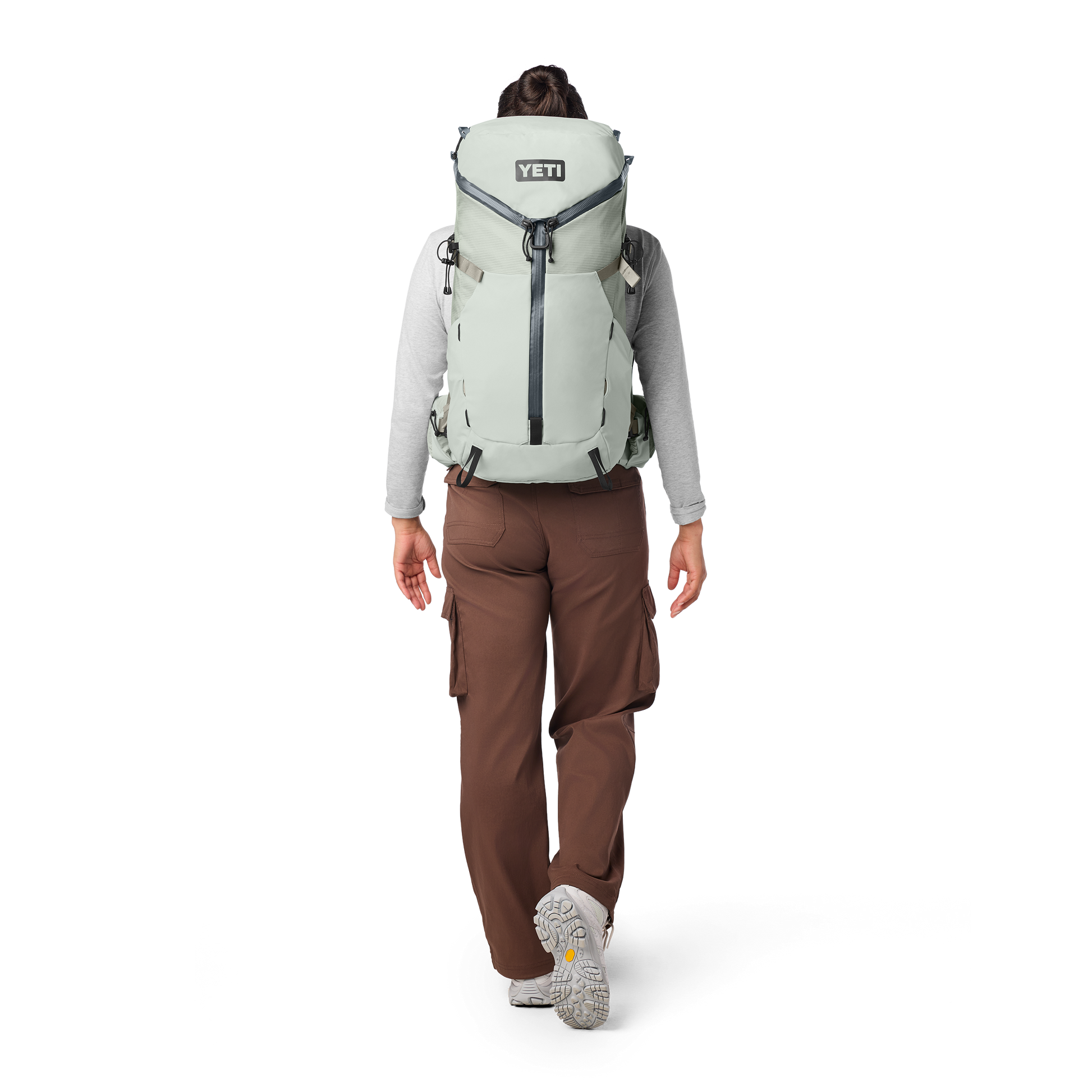 Person wearing a large backpack with 'YETI' branding on a white background