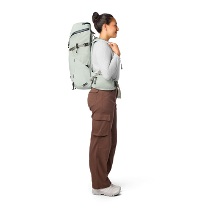 Person wearing a large green backpack on a white background