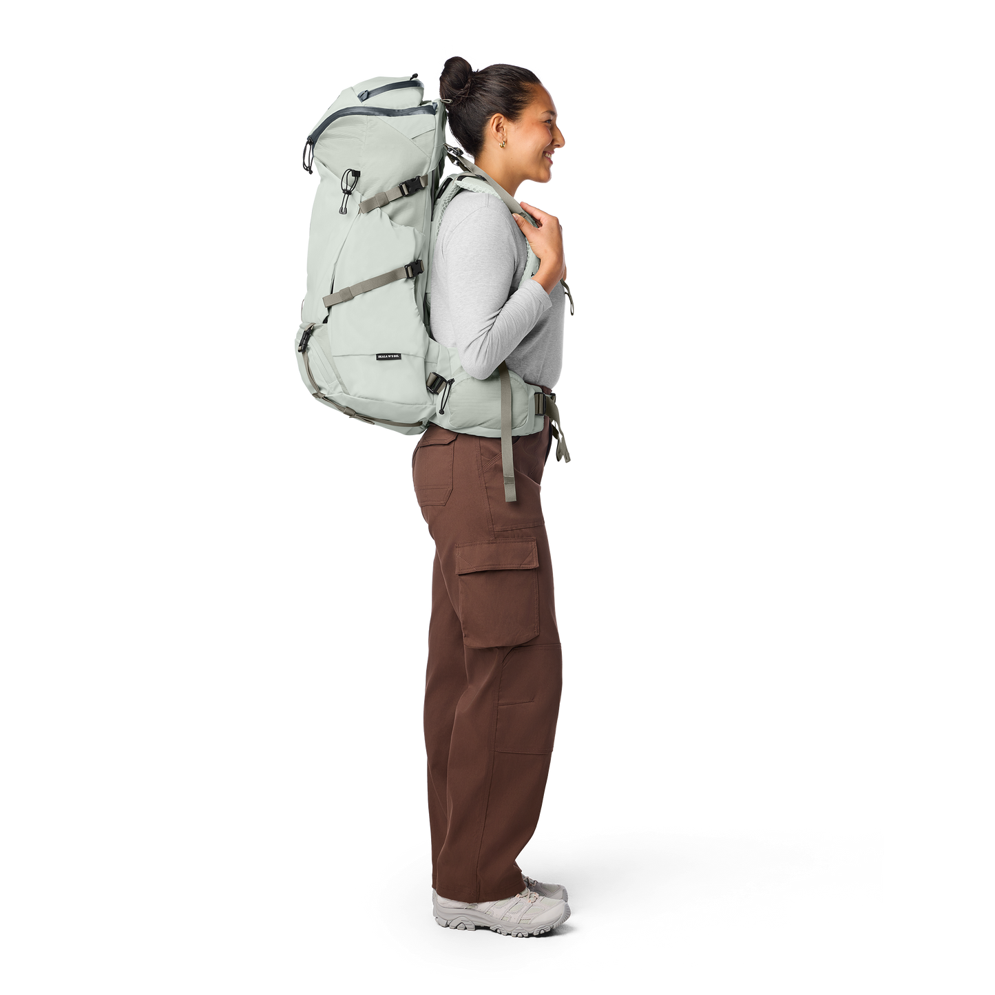 Person wearing a light gray backpack and brown pants on a white background
