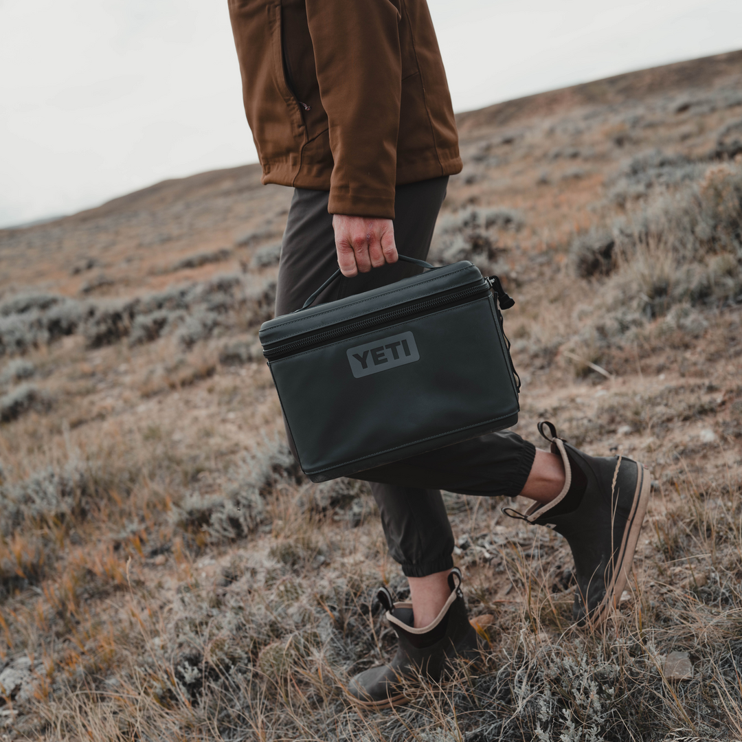 Person holding a YETI cooler in a desert landscape
