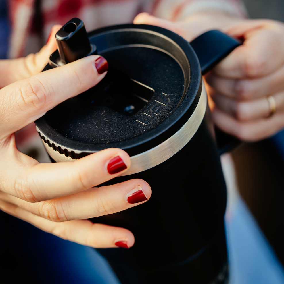 Person holding a black straw mug with red nail polish